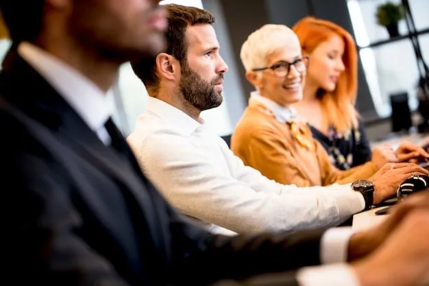A group of employees sitting in a conference room, attentively listening to a cybersecurity training session. The presenter is visible on a screen with slides about phishing awareness and password security.