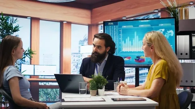 A group of economists or financial analysts in a meeting room, looking at charts and discussing economic data on a large screen. Emphasize data visualization and collaborative analysis.