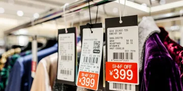 Close-up of department store clearance tags on designer clothing, indicating deep discounts