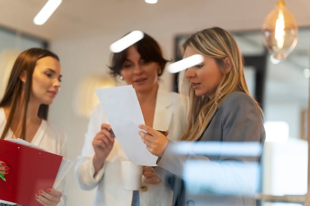 Close up shot of business owner reviewing and signing a grant application in warm office setting with blurred team members in the background.
