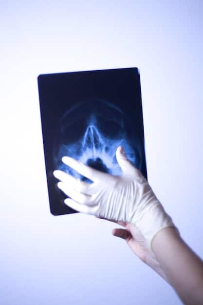 A close-up of a doctor's hand pointing at an area on a brain scan highlighted to show the reduction of amyloid plaques after treatment with the new Alzheimer's drug. The scan is displayed on a screen in a dimly lit medical office.