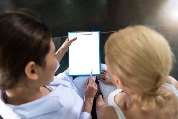 A close-up of a doctor's hands pointing to a chart during an annual wellness visit with a senior patient. The focus is on the interaction and the visual aids used in explaining the prevention plan.